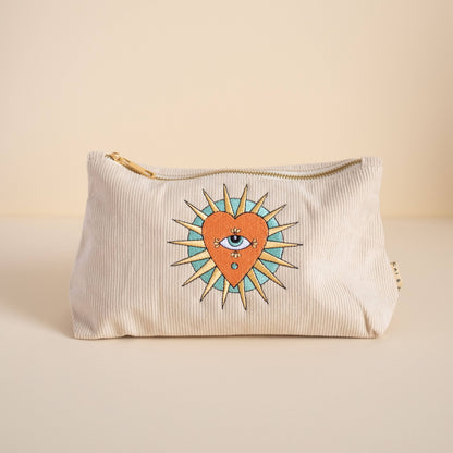 Stone-coloured medium corduroy pouch with a zip closure, featuring embroidered designs of a heart, eye, and sun. Fully lined for storing makeup, toiletries, or travel accessories.