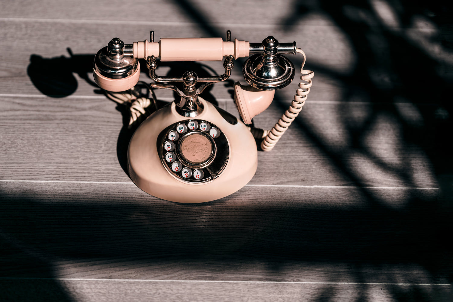 Old fashioned vintage peech coloured phone place on a wooden floor.