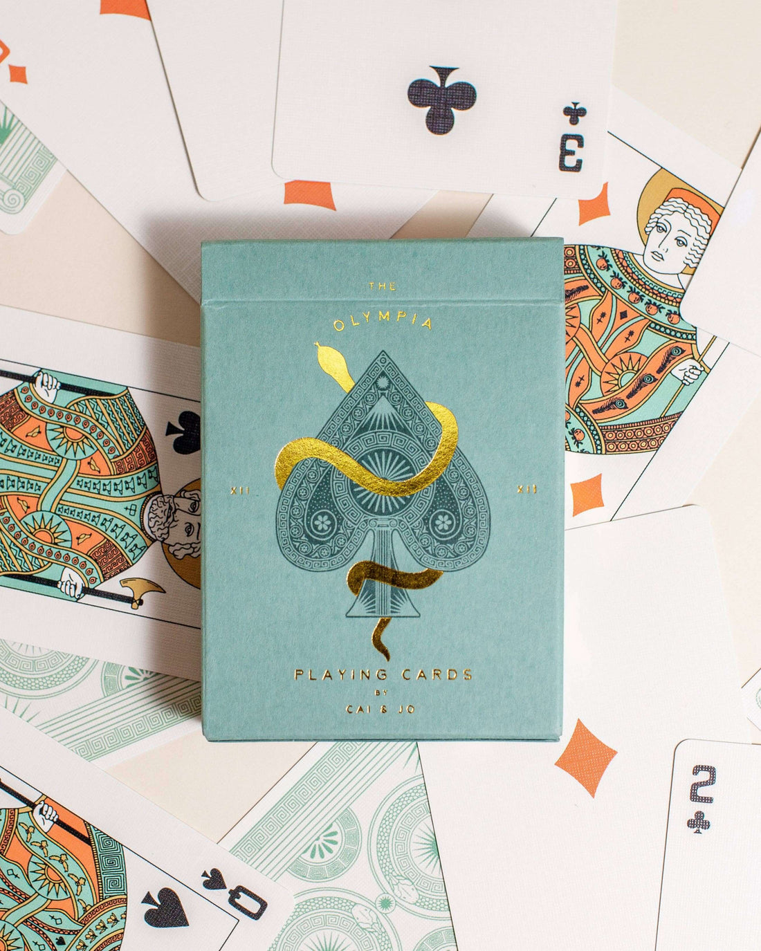 Premium-grade playing cards in sage green with a gold-foiled tuck box featuring an ace of spades design with a snake wrapped around it. Ideal for games and gifting.
