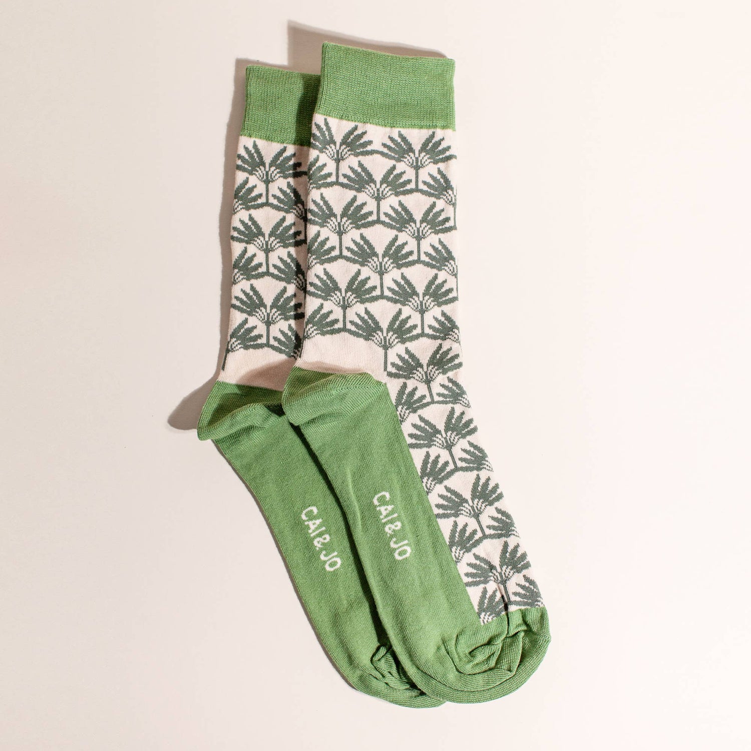 Green socks featuring an all-over palm tree design. Made from 75% cotton, one size fits most.