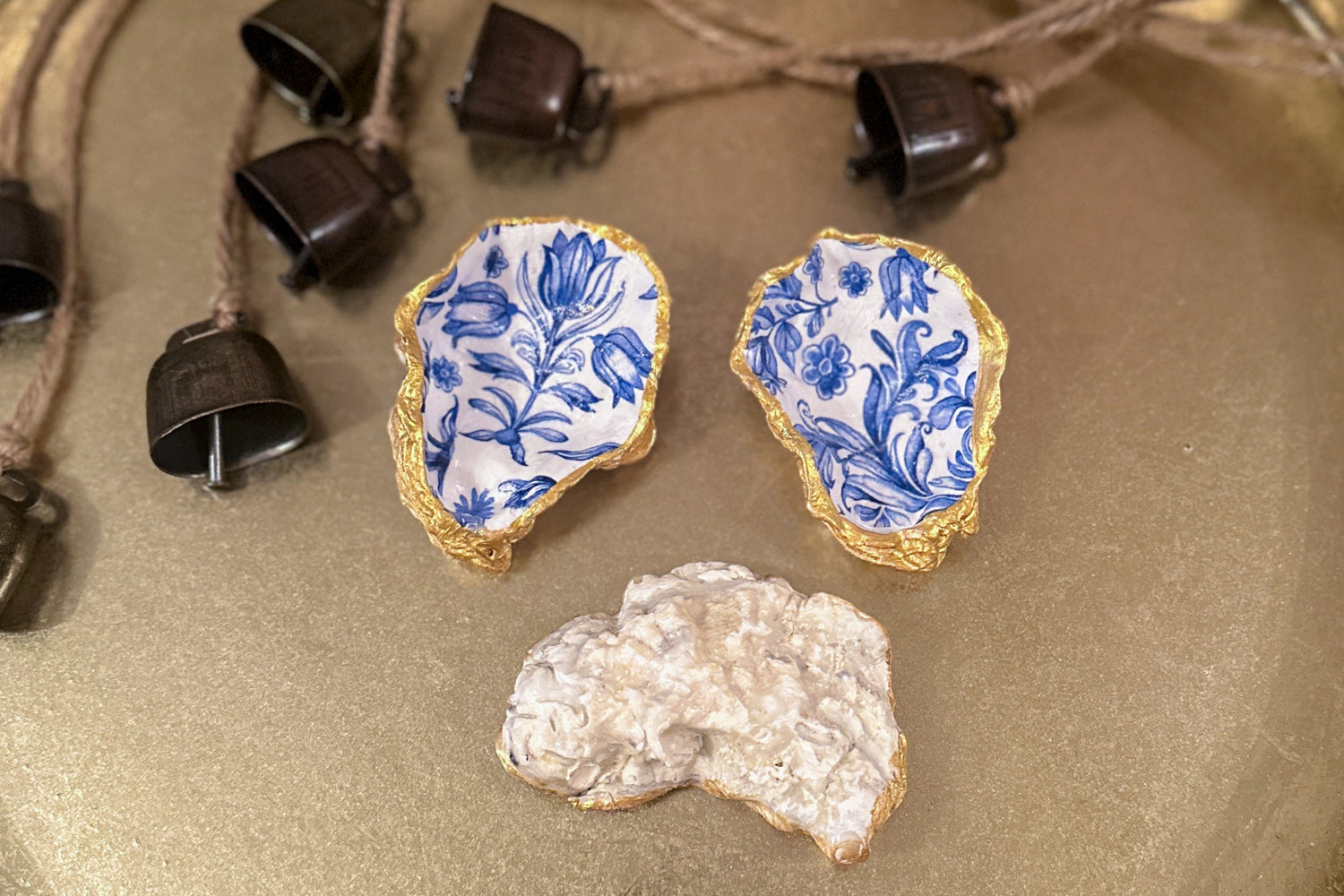 Set of three handmade oyster shell trinket dishes with blue and white floral designs, featuring a decoupage technique and hand-painted gold edges, ideal for home decor or jewellery storage.