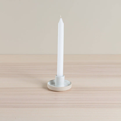 Handmade ceramic tapered candle holder in a natural oatmeal hue. Crafted by artisans using traditional techniques.