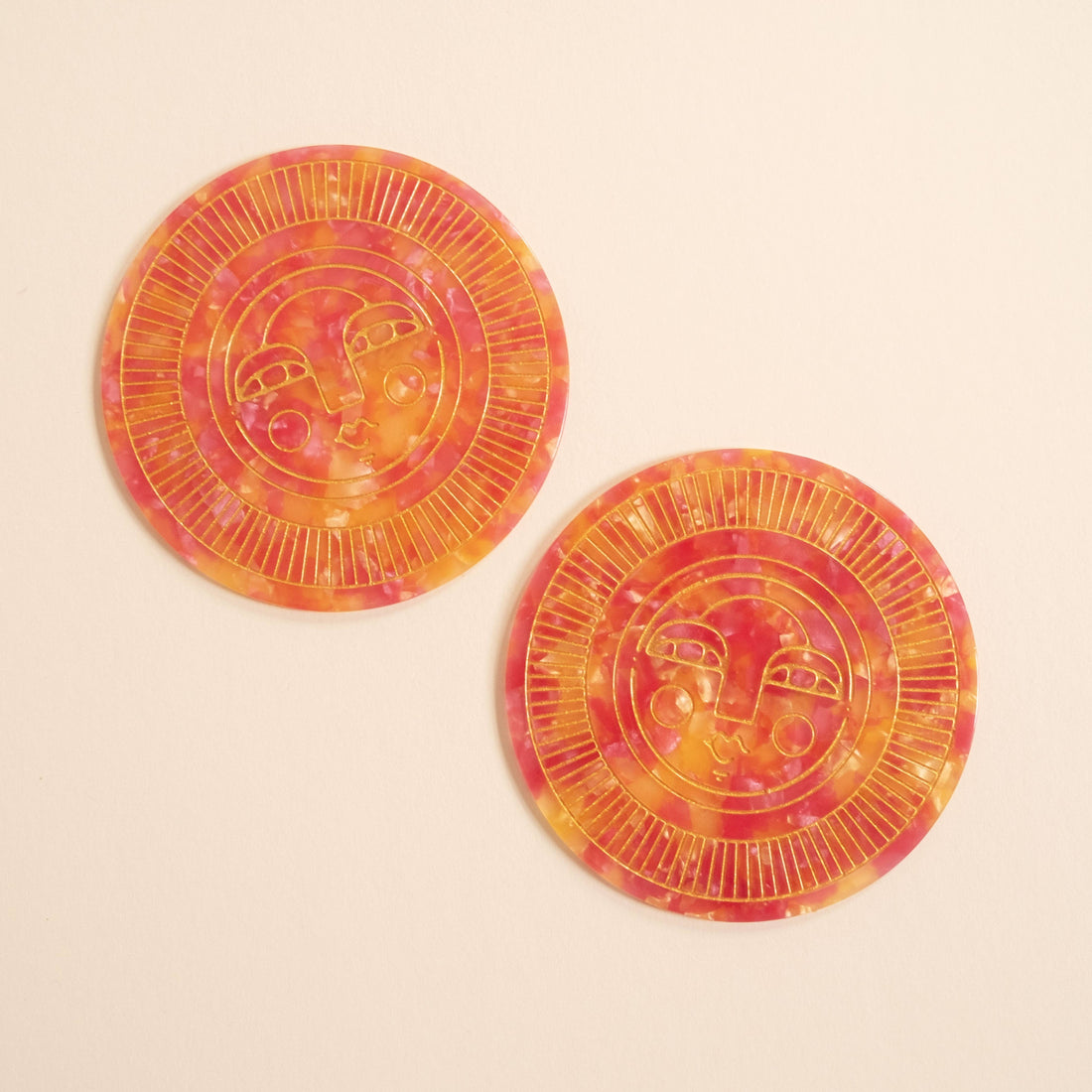 Set of two round handmade coasters in passionfruit pink acetate with engraved, gold-filled Sol face detail. Suitable for indoor or outdoor use. Perfect for home décor or barware.