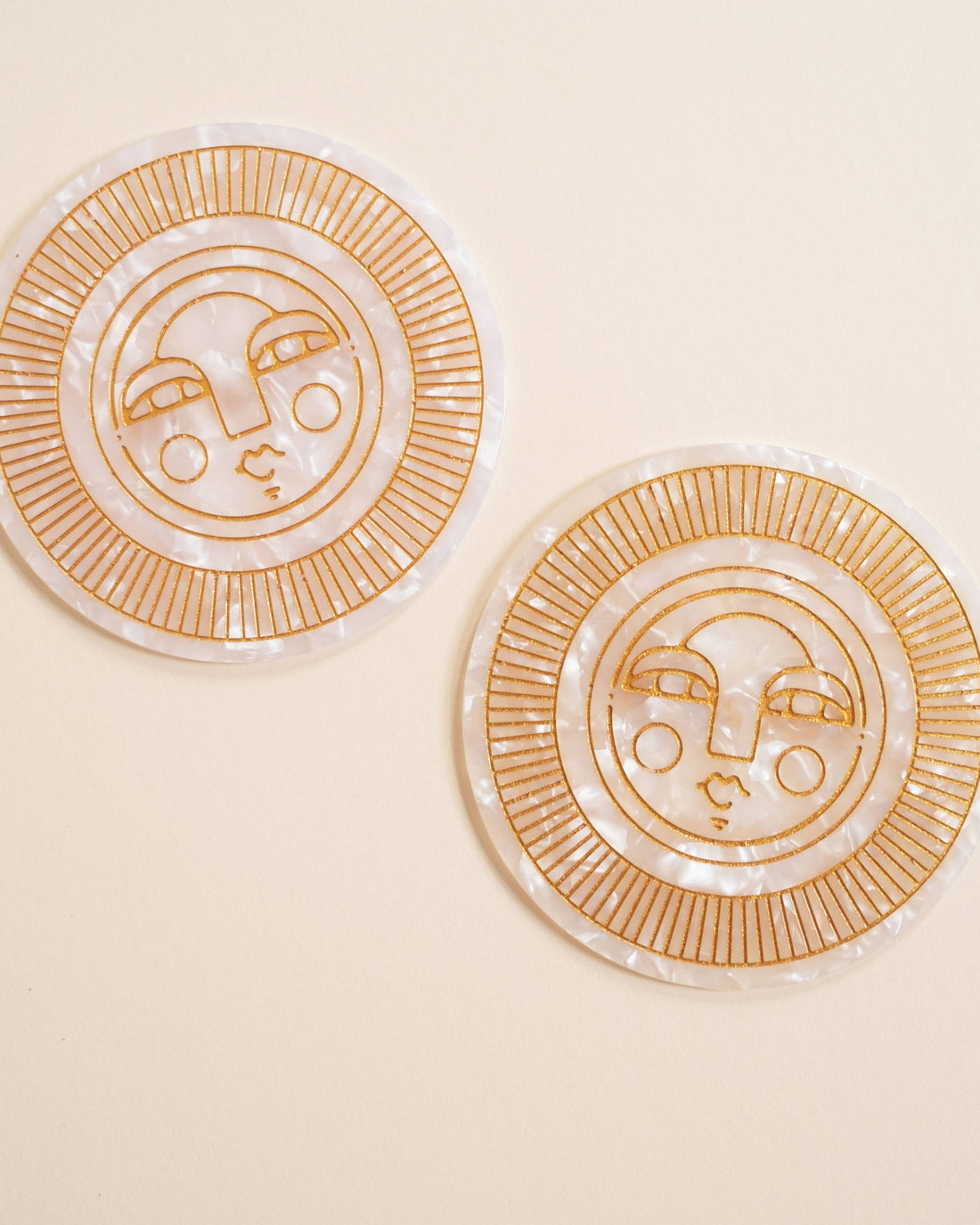 Set of two round pearl acetate coasters with engraved, gold-filled Sol face detail. Handmade for both indoor and outdoor use. Ideal for home décor or barware.