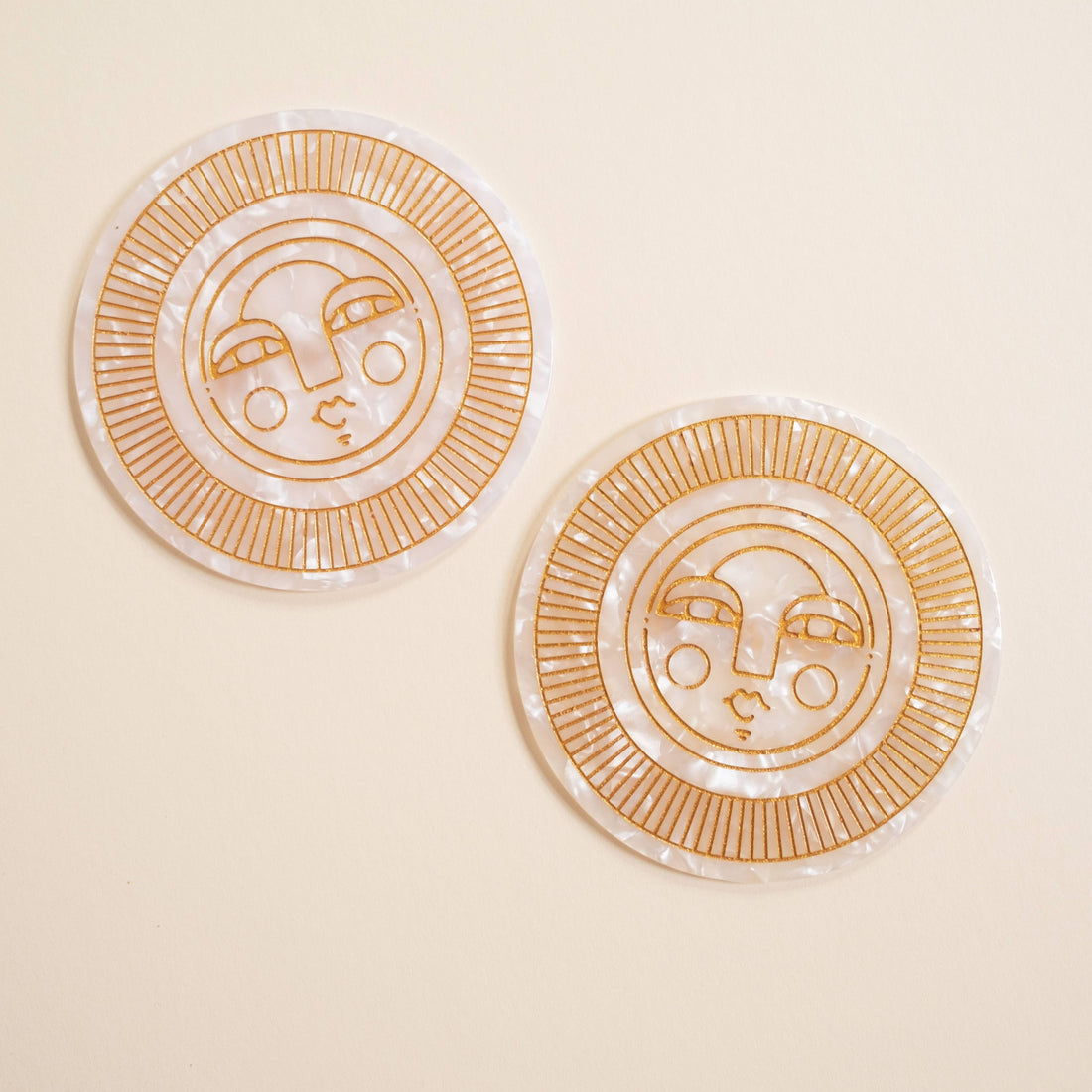 Set of two round pearl acetate coasters with engraved, gold-filled Sol face detail. Handmade for both indoor and outdoor use. Ideal for home décor or barware.