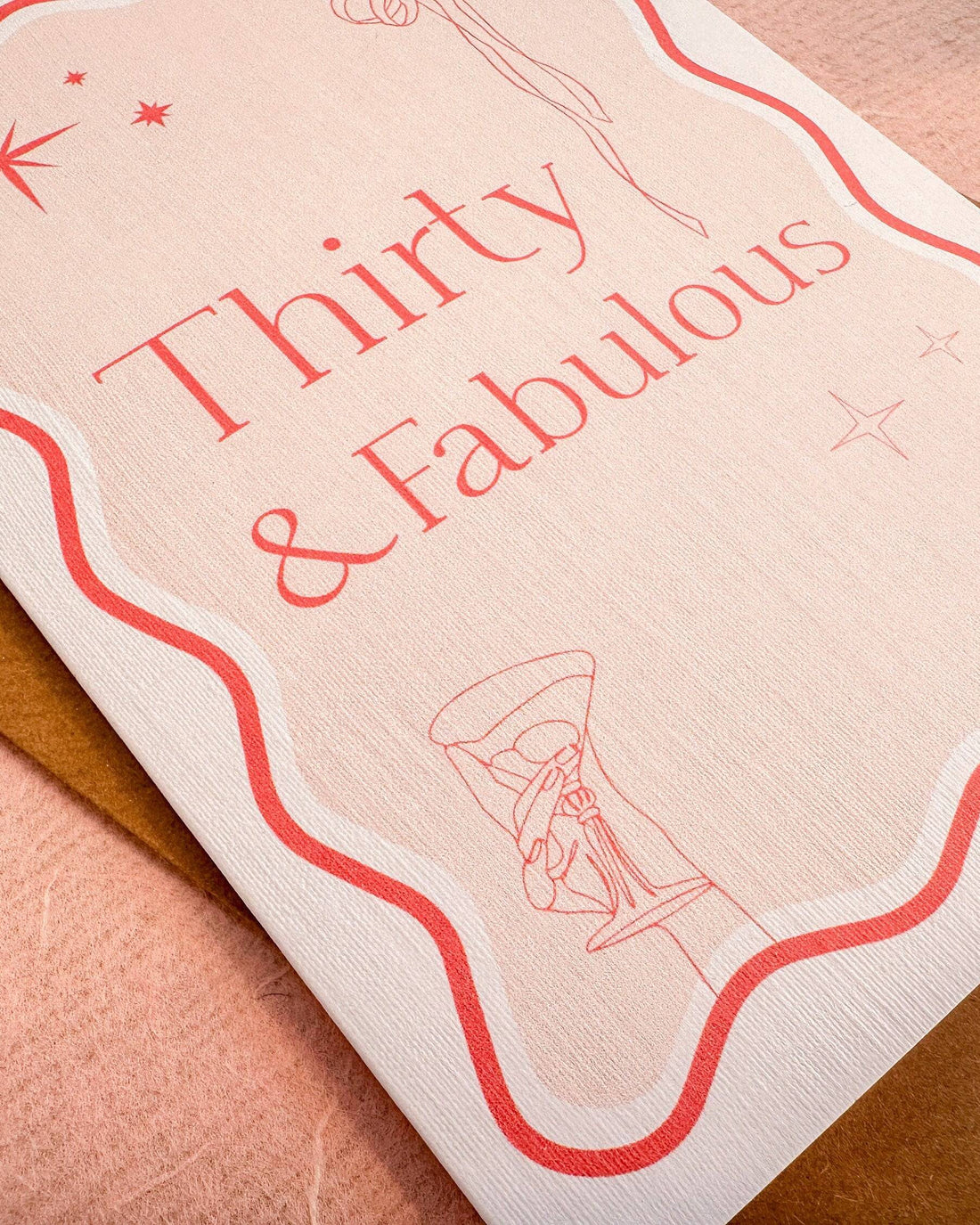 A6 handmade 30th birthday card featuring the words "Thirty & Fabulous" in pastel and bright pinks, with illustrations of a bow, stars, and cocktail. Includes a biodegradable cello wrap and Kraft envelope.
