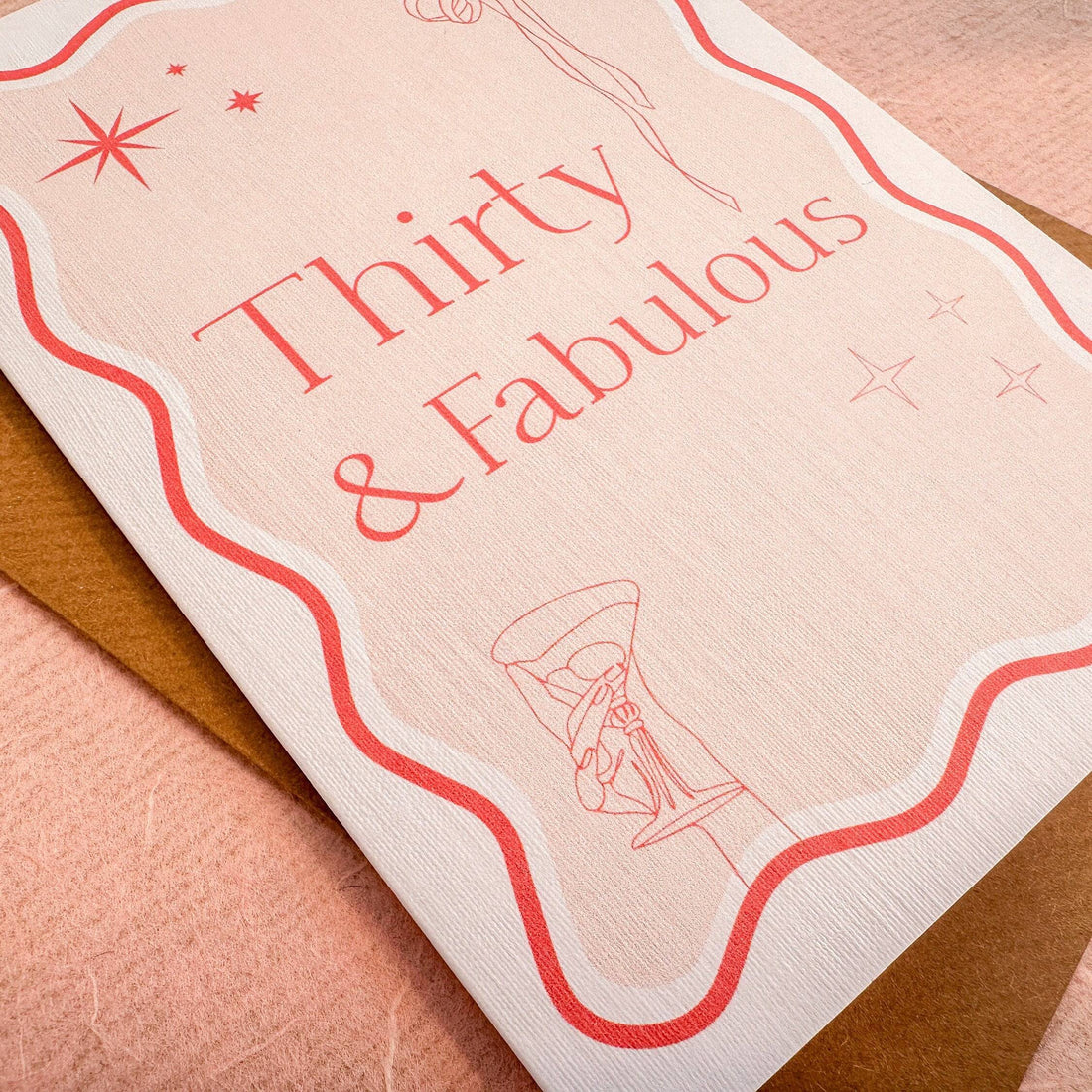 A6 handmade 30th birthday card featuring the words &quot;Thirty &amp; Fabulous&quot; in pastel and bright pinks, with illustrations of a bow, stars, and cocktail. Includes a biodegradable cello wrap and Kraft envelope.