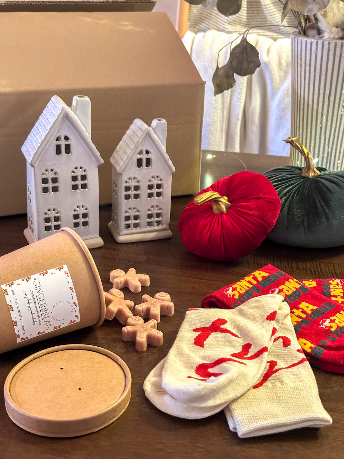 Luxury gift box featuring ceramic LED houses, velvet pumpkins, gingerbread wax melts, and cosy socks. A thoughtful and festive gift.